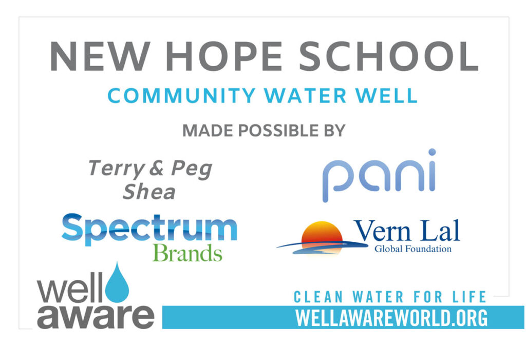 Sign displaying sponsors for New Hope School Community Water Well, including Spectrum Brands, Pani, Vern Lal Global Foundation, Well Aware, and Terry & Peg Shea, with a website link.